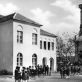 az általános Iskola (ma Dér István Általános Iskola) udvara, jobbra a Nepomuki Szent János-templom.